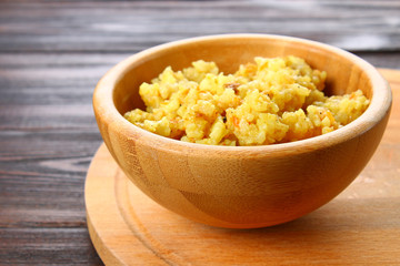 Rice pilaf with chicken, spices and parsley in a bowl on a wooden table.