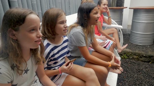 Diverse group of happy young girls sitting on a bench together