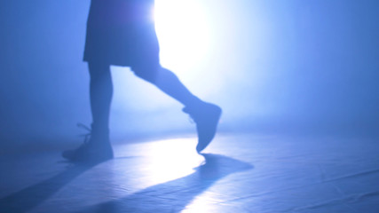 Bottom view of fighter training in the gym with smoke and light background. Silhouette of strong male boxer on dark background. Close up of athlete or sportsman moving fast while training