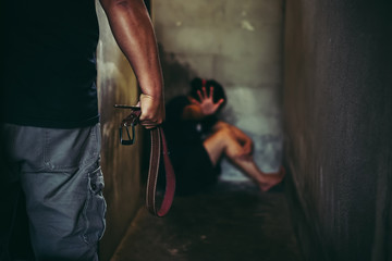 Man beating woman at home with a belt - concept photo of physical abuse