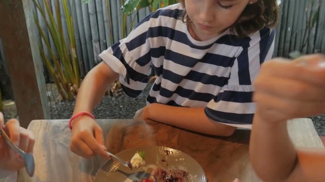 Close up of a young 11 - 12 year old girl getting a spoonful of dessert