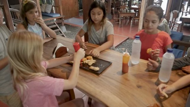 Group of boys and girls eating fast food together in a restaurant