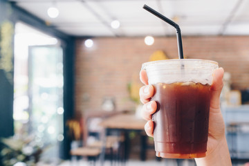 Cropped shot view of human holding a cup of Ice Americano.