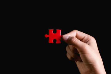 Hand holding piece of blank jigsaw puzzle