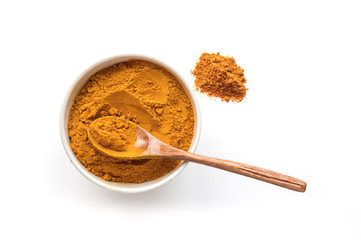 Isolated turmeric powder and wooden spoon. White background. Traditional indian spice. Top view. 