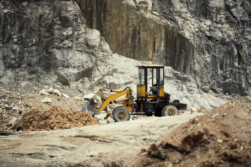 Heavy excavator on hill with rocks
