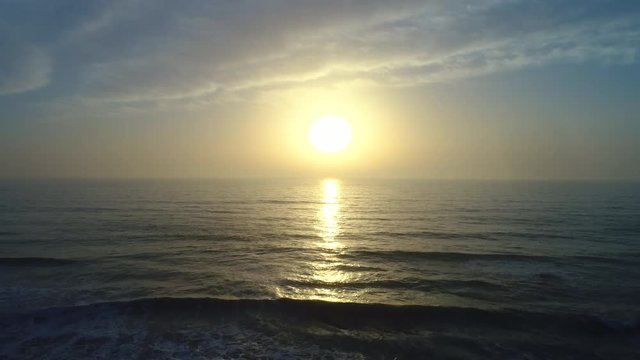 Aerial drone view of beautiful sunrise over the sea water and beach