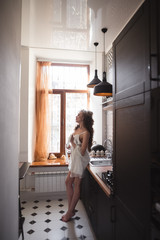 silhouette of a young beautiful girl standing in the kitchen by the window