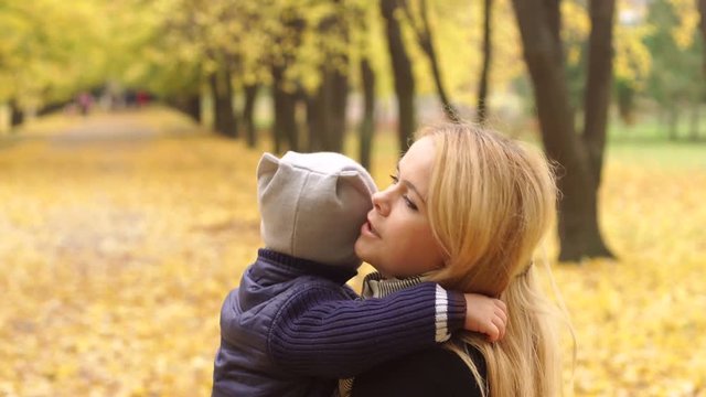 Mom and son in an autumn park. Mother and little son walking in autumn Park. The child gently hugs mom.