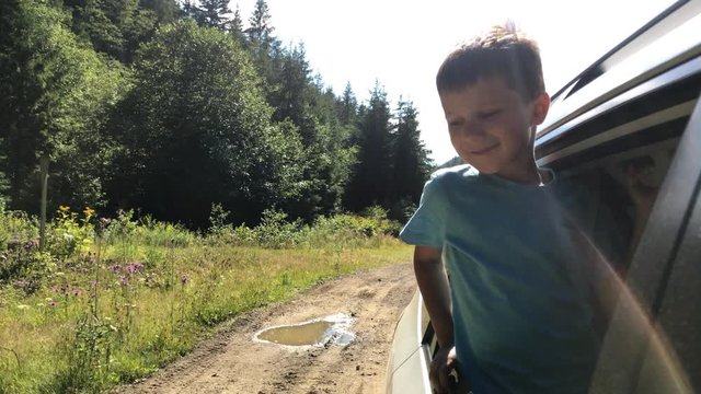 Curious small boy looking out window while driving in car
