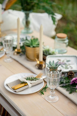 Decorated elegant wooden table in rustic style with eucalyptus and flowers, porcelain plates, glasses, napkins and cutlery