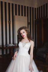 girl bride with curly hair standing in the room