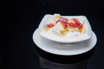 Strawberry ice cream on the white plate on the black background