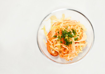 healthy food for diets: vegetarian vegetable salad from fresh cabbage, carrots, bell pepper and dill. Salad in transparent bowl on white background