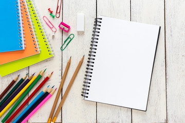 Empty notebook and colorful pencils on white wooden table