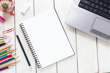 Empty notebook and colorful pencils on white wooden table