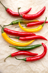 Vibrant  hot raw peppers on  crumpled paper, top view.