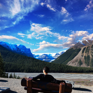 A traveler sitting in the bench and enjoying the scenery of the Rockies, Banff, Canada