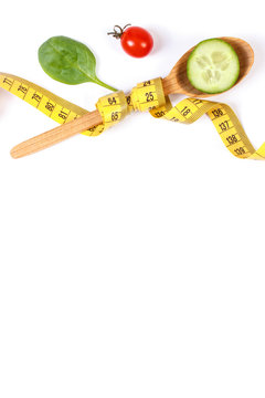Wooden spoon wrapped in tape measure and fresh ripe vegetables, concept of slimming, copy space for text on white