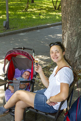 A middle-aged woman is walking in a spring park with a newborn baby.