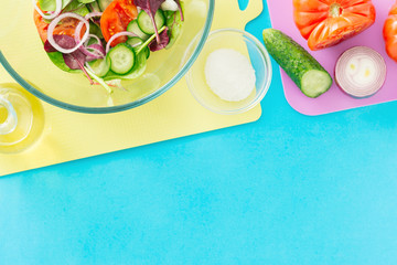 Ingredients for cooking summer salad on blue background with border, top view. Healthy food concept. Diet food