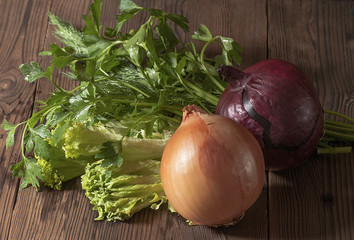 Parsley, dill, lettuce and two onions on a dark rustic table