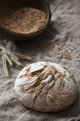 Freshly baked traditional bread and Wheat Ears on the Wooden Table. Harvest and Bakery concept. Close-up on a vintage wooden background, selective focus, shallow depth of field.