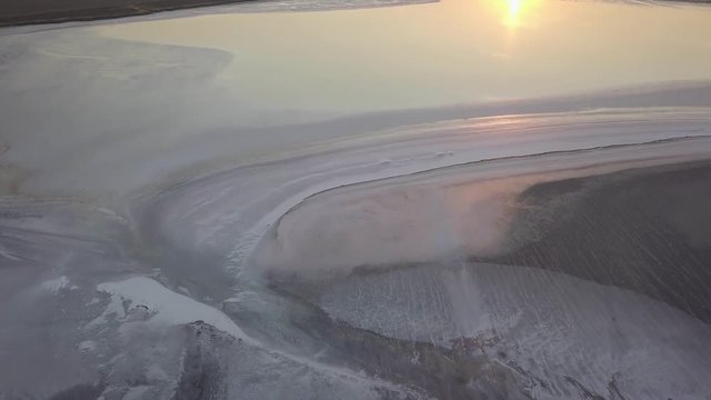 Aerial drone shot flying over vast cracked salt flats in azov sea, ukraine at sunset, mineral deposits.