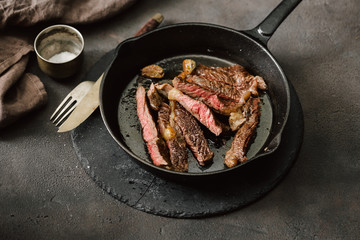 Slices juicy beef steak on vintage cast-iron frying pan
