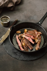Slices juicy beef steak on vintage cast iron frying pan