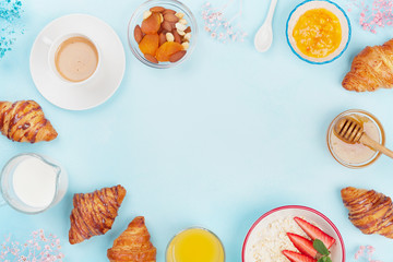 Morning continental breakfast with coffee, croissant, oatmeal, jam, honey and juice on blue table top view. Layout with space for text. Flat lay style.