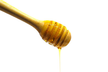 Dripping honey on wooden dipper or wooden spoon isolated on white background