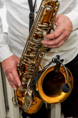 Fototapeta premium saxophonist in white shirt and black pants holds both hands brass saxophone with amp