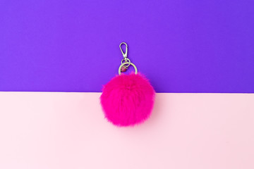 Fluffy keychain hot pink color on ultra violet and pink background. Flat lay