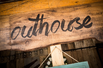 Outhouse sign on wooden board
