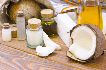 Natural herbal skin care products, top view ingredients coconut, white and yellow bottles with oil on table concept of the best all natural face moisturizer. Facial treatment preparation background