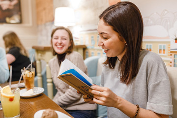 friends in cafe having fun and reading book