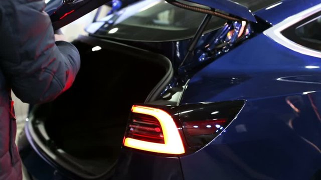 The man closes the trunk of an electric car