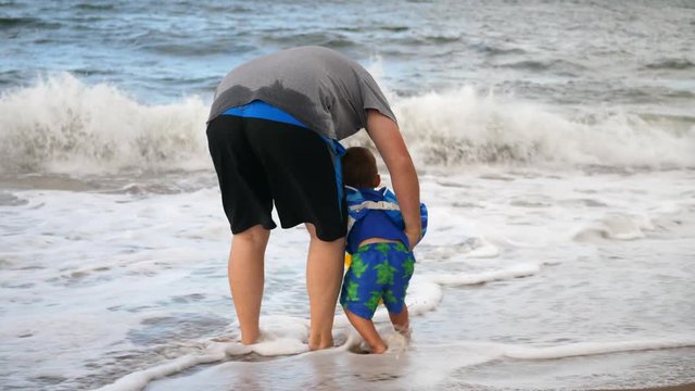 Family plays on fun sandy beach with waves