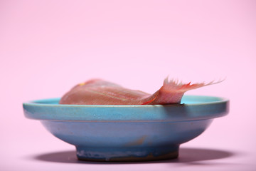 red Sea bream or Dorade rose in a turquoise bowl on pastel pink background