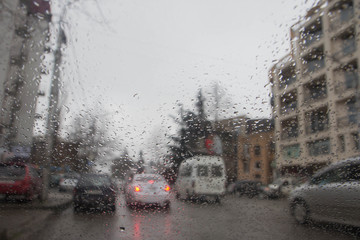 Rain drops on car glass. rainy weather, Evening. Rain drops on window, rainy weather. Blurry car silhouette