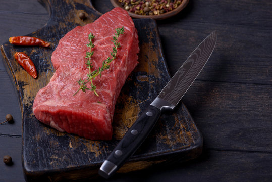 Raw beef steak with thyme and pepper and knife
