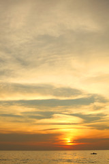 Naklejka na ściany i meble dramatic colorful sea sunset with sun setting on water lonely boat on horison