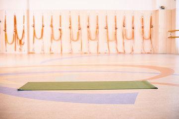 Empty space in fitness center, brick wall, natural wooden floor, modern loft studio, unrolled yoga mat on the floor.