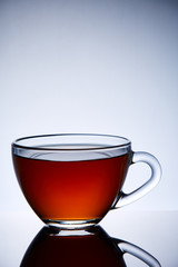 Glass transparent empty teacup on a light grey background, close-up, vertical.