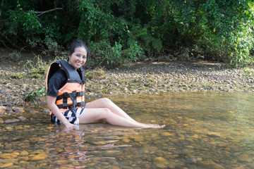 asian female in life jacket sitting near river in kanchanaburi thailand., on the Waterfront