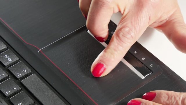 Close up of woman hand touching a touchpad on laptop