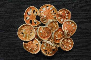 Dried herbs and dried bael fruit, Top view of bael dry on the wooden floor, Slices of bael fruit for make bael juice on the dark table.
