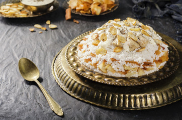 Arabic cuisine; Jordanian Chicken Mansaf of white rice and crispy fried bread topped with chunks of chicken,toasted almond and garlic yogurt sauce on copper plate.