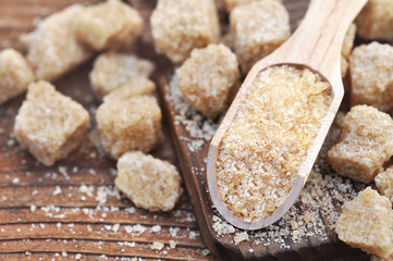 Spoon on brown unrefined sugar, granulated and cubes, selective focus